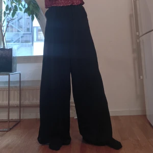 Silkiga vida byxor - Vida svarta byxor i silkigt skönt material. Långa i benen(108 cm), Jag har ett par till som jag klippt av lite i benen (är 172 cm) så fina och sköna!!  Resår i midjan så passar S-M. 