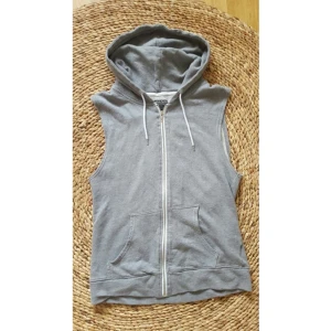  - Grå sweatshirt väst, mönster på ryggen, lagom storlek på luva, två fickor fram och en fungerande dragkedja!