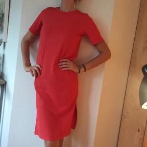  - Tshirtklänning från Asos i röd/rosa korallfärg. Två slitsar vid sidorna, köpt i våras och aldrig använd. Storlek 36. Swish och du står själv för frakt! (Jag är 180cm lång)