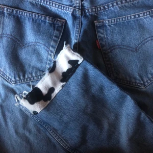 Levis 501 med cowprint detaljer - Vintage levis 501 som jag sytt på ko mönstrade detaljer för hand. Saknar dragkedja och lappen är sliten därav det billiga priset. Enkelt stt sy på dragkedja/ knappar.Själva jeansen är i bra skick. Frakt 44kr. Kontakta för mer info. Priset kan prutas