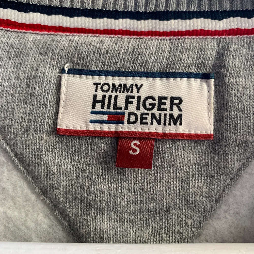 Grå sweatshirt från Tommy Hilfiger med snyggt tryck på både fram- och baksida. Säljer pga att den tyvärr har blivit för liten! Väldigt mysigt material på insida vilket gör den perfekt för höst/vinterväder! NYPRIS: 899kr . Hoodies.