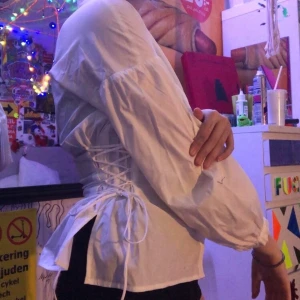 Skjorta med knytning på sidorna  - Fin vit skjorta med knytningar på sidorna som påminner som en slags korsett, köpt på Lindex för typ 200kr, ser lite genomskinlig ut men skulle inte säga att den e det irl. Köparen betalar frakt 