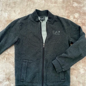 Emporio Armani kofta/tröja - Tröja från Emporio Armani med dragkedja. Använt skick men inga defekter. Strl 160 (14 år). Frakt ingår ej.