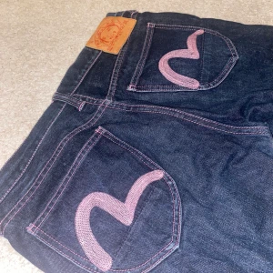 EVISU JEANS - !Buda i kommentarerna! Säljer pga fel stl. Obs, Tydliga tecken på användning. Finns 3 slitningar, varav den jag visar är den mest tydliga. Hör av dig om du vill se fler bilder eller undrar ngt. Stl 32. Midjemått ca 90 cm, innerbensmått 85 cm. 