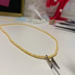 här är ett halsband med en metall-blixt med gula fina pärlor 💫