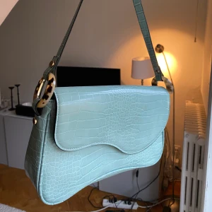 Kort Axelväska - Kort blå axelväska köpt för 250kr förra sommaren på topshop i London💕 skitcool blå ”krokodil”-skinn, säljs pga att jag inte får användning av den längre tyvärr❤️