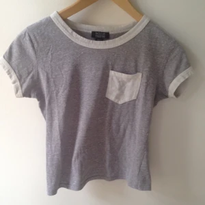  - Grå kortare T-shirt med vita detaljer vid krage och ärm+ficka från Pacsun 