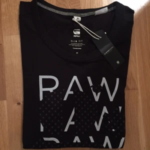 - Svart snygg stilren T-shirt från G-star. Lapp kvar, den är aldrig använd. Storlek M, sitter snyggt på mig som är 36-38. 