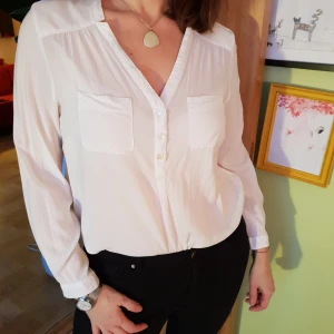  - En vit blus med fickor, i gott skick.  Går att hämtas i Gamla stan eller skickas via post.