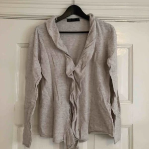  - Storlek L. Sitter fast med 2-3 hakar på framsidan som går att öppna om man vill ha den öppen istället. Bomulls-viskos-blandning, lappen finns tyvärr inte kvar. Bra skick, kan finnas någon noppa någonstans.