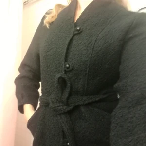 - Fantastisk svart höstjacka i 100% ull från vintagebutik, inköpt i USA. Klotformade knappar, kraglös, skärp i midjan. Jag har strl 36 och den passar mig bra! Fodret har spruckit vid ena axeln men det går nog lätt att laga. Fler bilder finns! Säljes pga brist på plats.