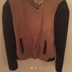  - Fin jacka med skinimitation på ärmarna och tyg i mitten. Också lite sned knäppning med dragkedjan. Väldigt snygg. 