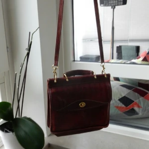  - Brunröd skinnväska med gulddetaljer. Lite sliten och använd med fortfarande i snyggt second hand - skick! 