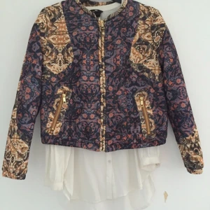  - Aldrig använd jacka i bombermodell. Kortare i längden, dragkedjorna är guldfärgade. 