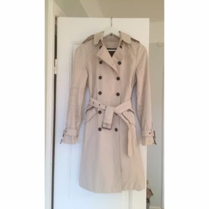  - En tidlös lång trenchcoat med bält. Ljus i färg, vackra detaljer och bra passform. Köpt från Zara för 1000 kr. 

Höger ärm är litet smutsig (bild 3) och jag har inte vågat tvätta den, men det står att 30 graders tvätt borde gå bra. Därav låga priset.