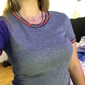 Grå t-shirt  - Grå (typ ribbad?) t-shirt med rosa och svarta detaljer på halsen och ärmarna, från hm, 155kr inklusive frakt