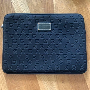 Marc Jacobs datorfodral - Jättefint datorfodral från Marc Jacobs! Passar en 13 tumms dator. Har soverdetaljer och är i bra skick🥰 själva knapparna på emblemet har förslitits om blivit bronslag, men i övrigt i bra skick! Budgivning till tisdag (28/7). Köpare står för frakt!