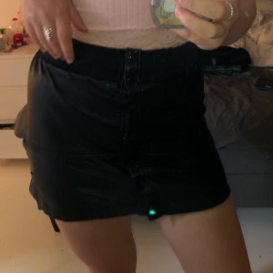 Läder kjol - Svart läder kjol med knappar på framsidan, ganska kort o stretchig längst upp, aldrig använt 