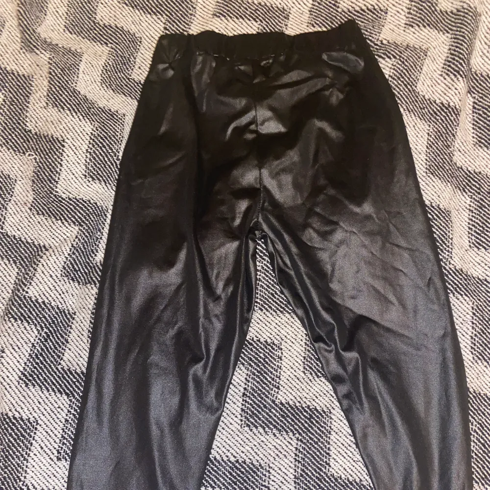 Svarta byxor i glansigt material, typ samma stil som skinnbyxor. Resår i midjan inte använda.. Jeans & Byxor.
