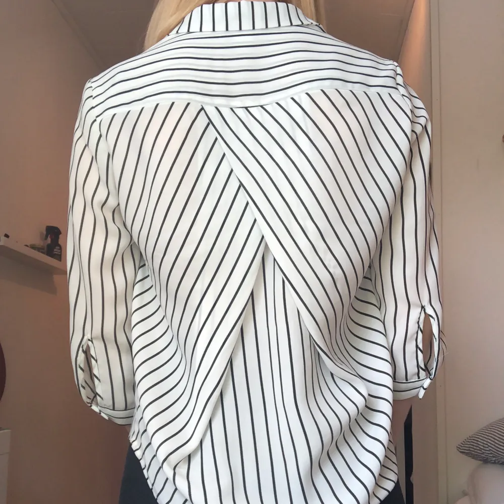 En svart-och vitrandig skjorta med krage en överlappning i ryggen. Storlek XS men fungerar även för en storlek S. Använd ett fåtals par gånger. Köparen betalar frakt :). Skjortor.