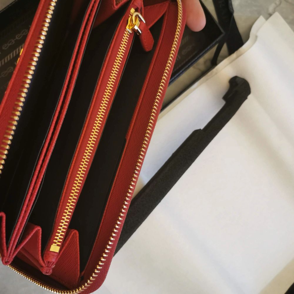 Hel ny och oanvänd plånbok från Prada i den lyxiga färgen röd. Det är en gåva som aldrig har kommit till användning och endast legat nedpackad i sin kartong. Inköpt på Prada birger jarlsgatan i Stockholm. Kvitto, presentkartong, snöre, papper och påse . Accessoarer.