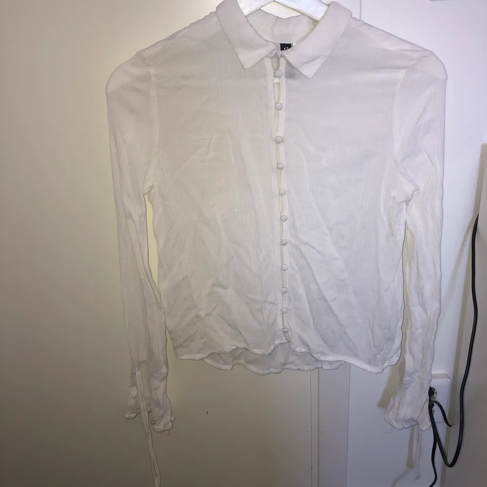 En somrig, vit skjorta i skönt bomullsmaterial. Går att öppna och stänga (beror lite på hur man själv vill styla den). Det finns även söta detaljer längs händerna. . Blusar.