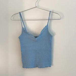 Blått linne från Gina Tricot, strl XS - Ett sött blått linne som är i väldigt bra skick då det endast är använt ett fåtal gånger. Det är även i ett väldigt stretchigt material och ser därför mindre ut. Orginalpris, 99 kr. Frakt ingår inte i priset.