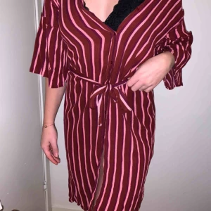  - Midiklänning som knyts i midjan, en slits på varje sida och knäppning fram