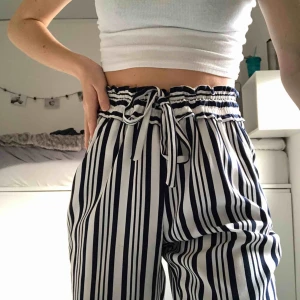 Randiga sommarbyxor - Vit och marinblå randiga byxor med snören i midjan. Byxorna är från Zara. Svala och perfekta på sommaren. Säljer dem för att de är lite förkorta för mig som är 170cm
