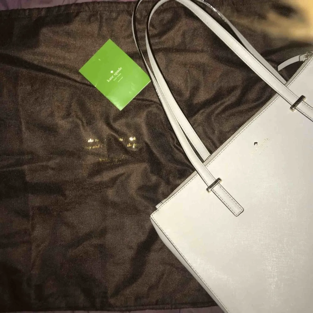Ljus grå/naturfärgad Kate Spade väska i bra skick. Köpt i New York. Original pris: 4000kr. Dustbag och care card medföljer.. Väskor.