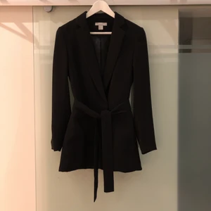 Kavaj HM - Kavaj från HM med axelvaddar och knytning i midjan. Lite längre modell. Jag är 172cm och den slutar strax nedanför rumpan på mig. 