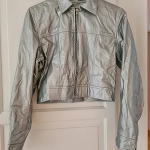 Vintage jacka - Trendig vintage jacka i färgen silver. Snygg kort retro modell. Säljer den då jag växt ur den men av nostalgiska skäl haft den kvar. Tippar på att det är en strl S/M. Finns ett litet märke på jackan med namnet Modelli. Möts upp eller skickas.