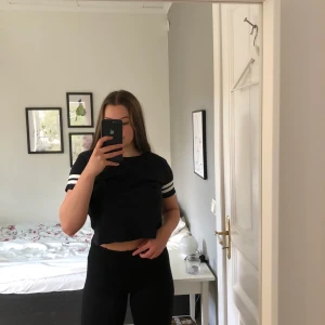 Svart tröja storlek S - Svart croptop med vita sträck på ärmarna.