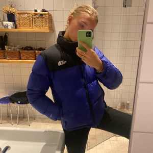 The North Face Dunjacka - Blå/svart Jacka i nyskick. Köpt förra året men endast använd vid två tillfällen. Nypris 2800. Strl M men lite mindre i strl. Jag är 175cm lång så du ser passform på bilden. Högst bud vinner 