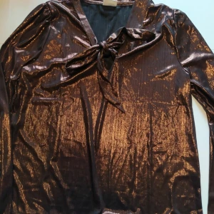 Kopparglänsande blus strl L nyskick - Med knytning. Färgen är mkt mer slående i verkligheten. Tunt material.
