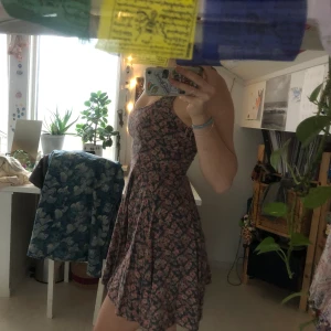 Blommig klänning - En fin blommig sommarklänning! En fin dov ton på färgerna med ett skönt tyg. Sitter tightare runt bysten och midjan och faller fint. Från märket Kimchi Blue, i storlek S.