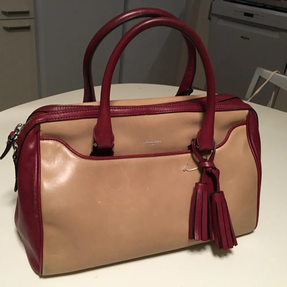 Elegant Coach beige/ röd läder handväska. Superfint och väldigt exklusivt och har många praktiska fack både med och utan gragkedja.Mått: 32cm x 25 cm x 17cm. Väskor.