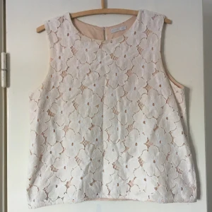  - Vacker mönstrad blus med vita blommor och ljust rosa undertyg. Ganska vid modell så passar L med beroende på hur lös du vill att den ska sitta.  