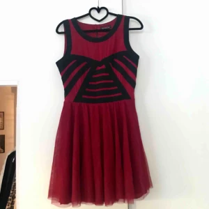  - Röd klänning med svarta detaljer, inköpt i Australien.  Finns att hämta i Uppsala. Kan även posta, säljaren betalar då frakt