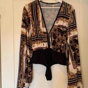  - Mönstrad body med utsvängda armar storlek M.