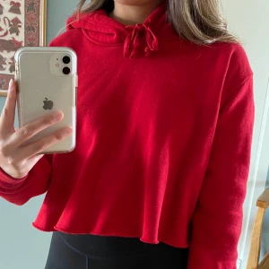Röd hoodie från Brandy Melville - Såå skön hoodie från Brandy Melville! Den är avklippt där nere och lite kortare fram än där bak. Strl one size enligt Brandy Melville. Bara använd ett par gånger. Kan mötas upp i Malmö, annars står köparen för frakten🥰