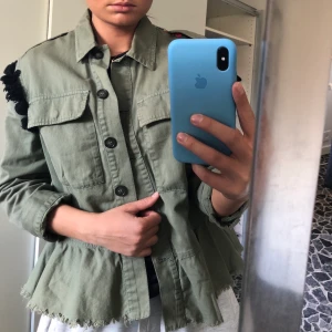 Vårjacka  - Speciell vårjacka som sticker ut. Framsidan är grön men baksidan har ett jättefint mönster i massor av färger. Längst ner är det volang. Ett favoritplagg som inte kommer till användning längre. Frakt tillkommer! 