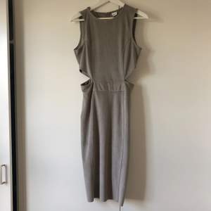 Grå vadlång klänning i mockaimitation med cut-out detaljer . Använd 1 gång , så gott som ny! Ev frakt betalas av köpare.