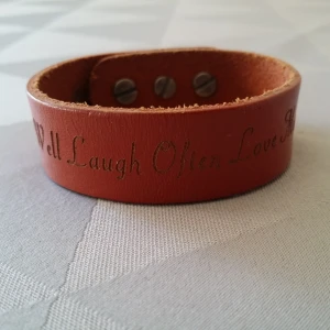  - Läderarmband med text "Live well laugh often love much" och en liten fågel.  Frakt: 9 kr