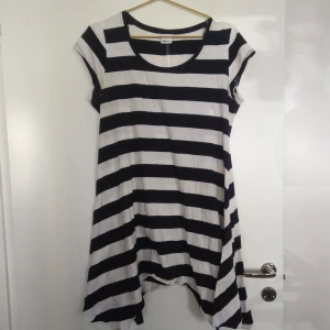  - Randig lös klänning från Gina Tricot i vit och mörkblått, nästan svart. Går lite längre på sidorna. Korta ärmar. Gratis frakt!