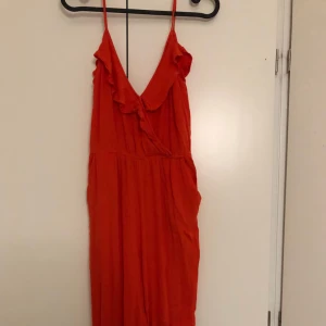 - Röd jumpsuit med djup v i ryggen
