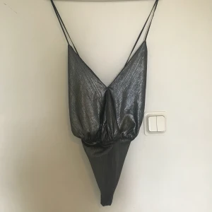  - Silvrig body storlek S. Använd 2-3 gånger, urringad och öppen rygg :)