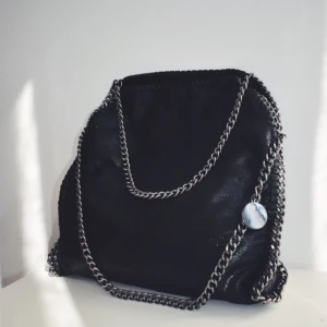  - En snygg väska som är utsmyckad med kedjor. Oanvänd, prislappen finns kvar på väskan. 