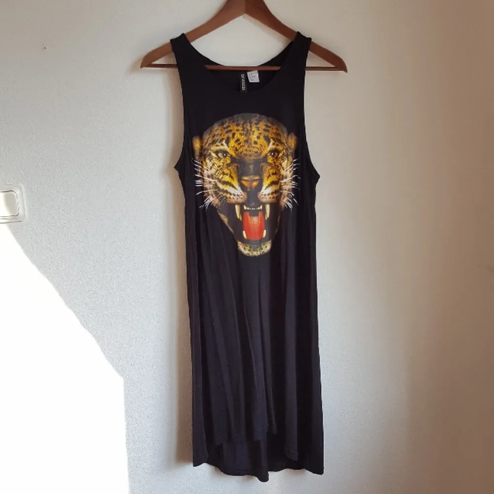 Svart knälång klänning med leopardmotiv framtill, i storlek 38. Något längre baktill. Oanvänd, endast prövad :). Klänningar.