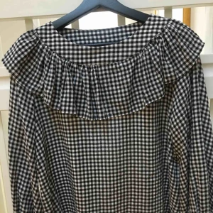 - Ens svart/grå/vit rutig volang blus i linnetyg. Liten i storleken och passar därför S likväl som M. Mycket söt topp som inte fått den uppmärksamhet den förtjänar. 